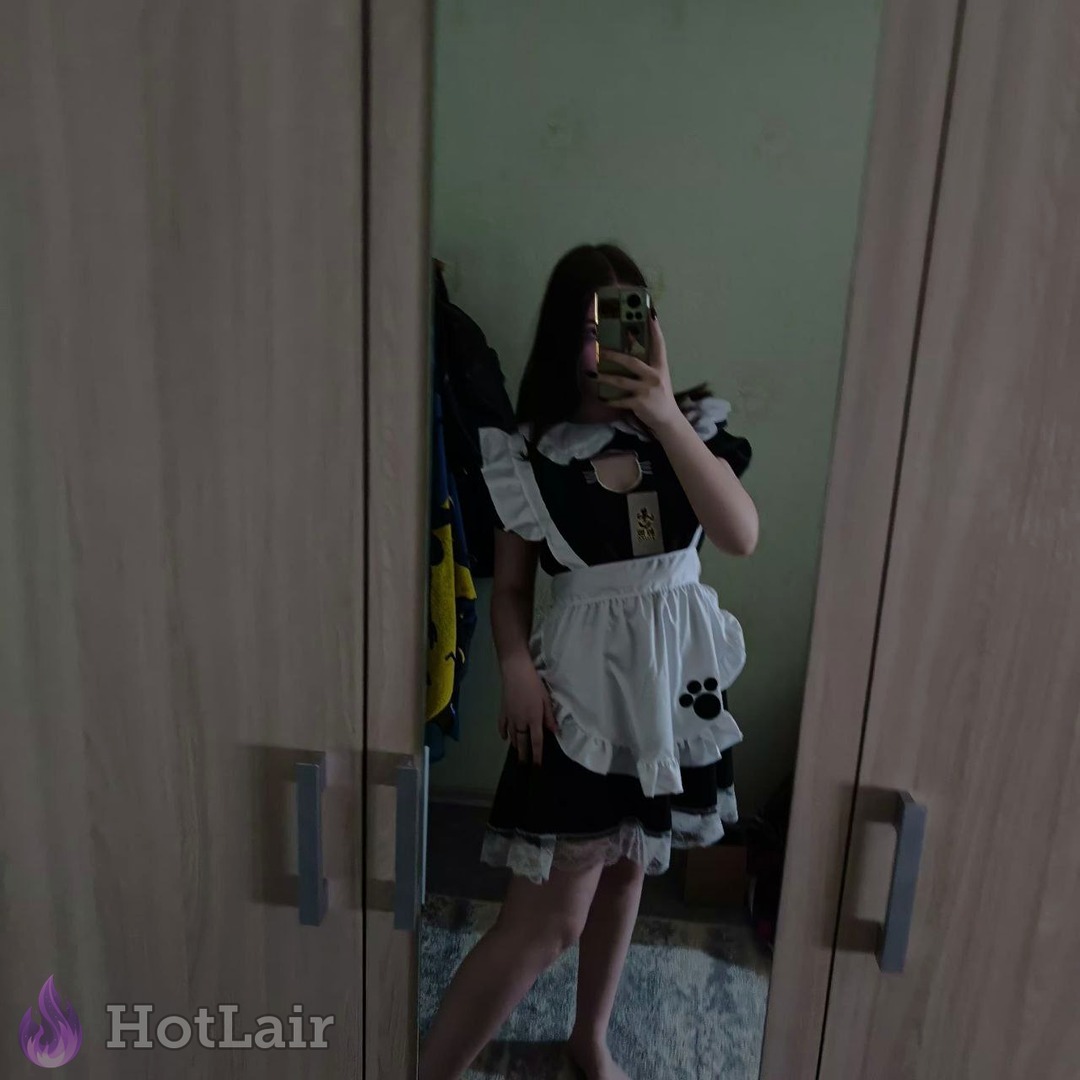 Selfie en espejo de una con uniforme de maid negro y blanco sosteniendo un teléfono