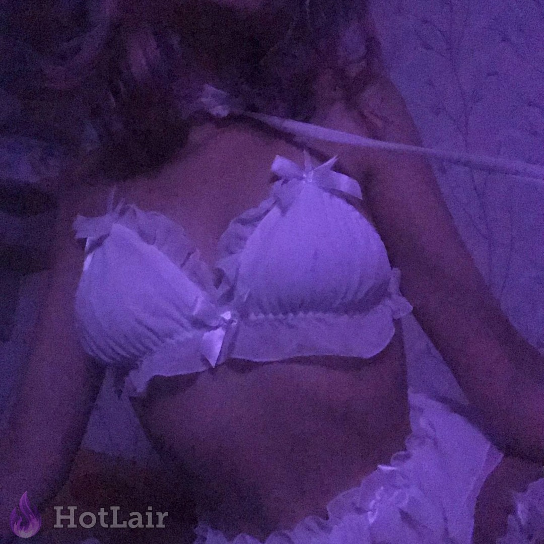 Una yace en la cama usando un sostén blanco con volantes y lazos