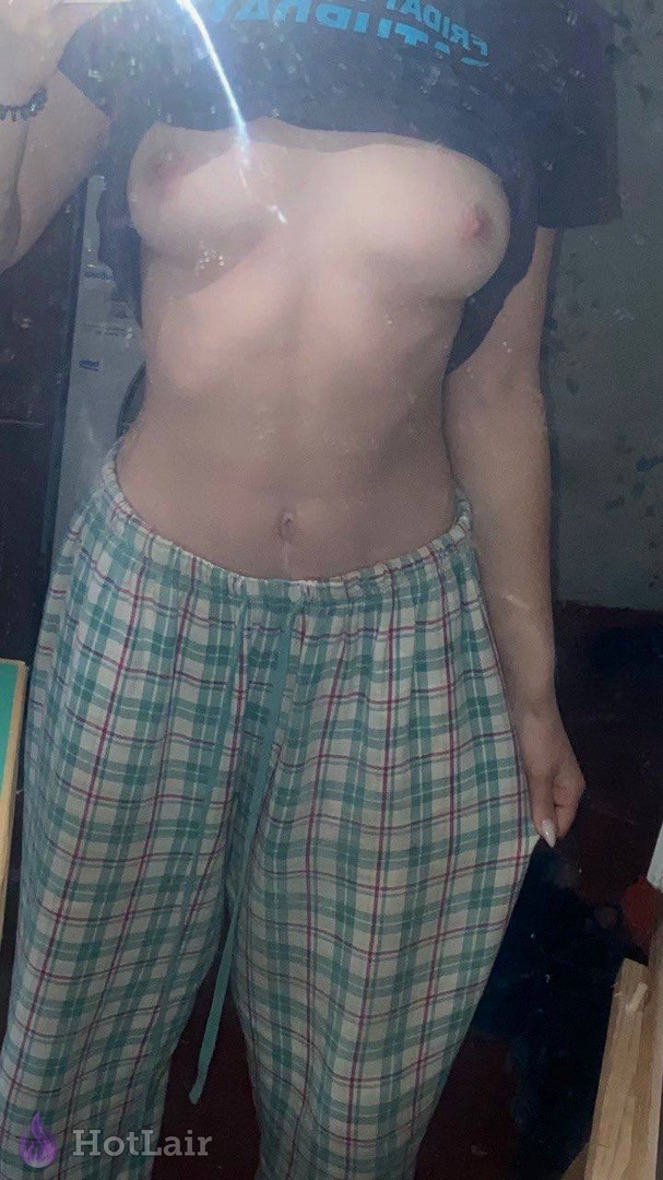mojada levantando una camiseta negra para mostrar sus pechos mientras usa pantalones de pijama a cuadros verde y rojo