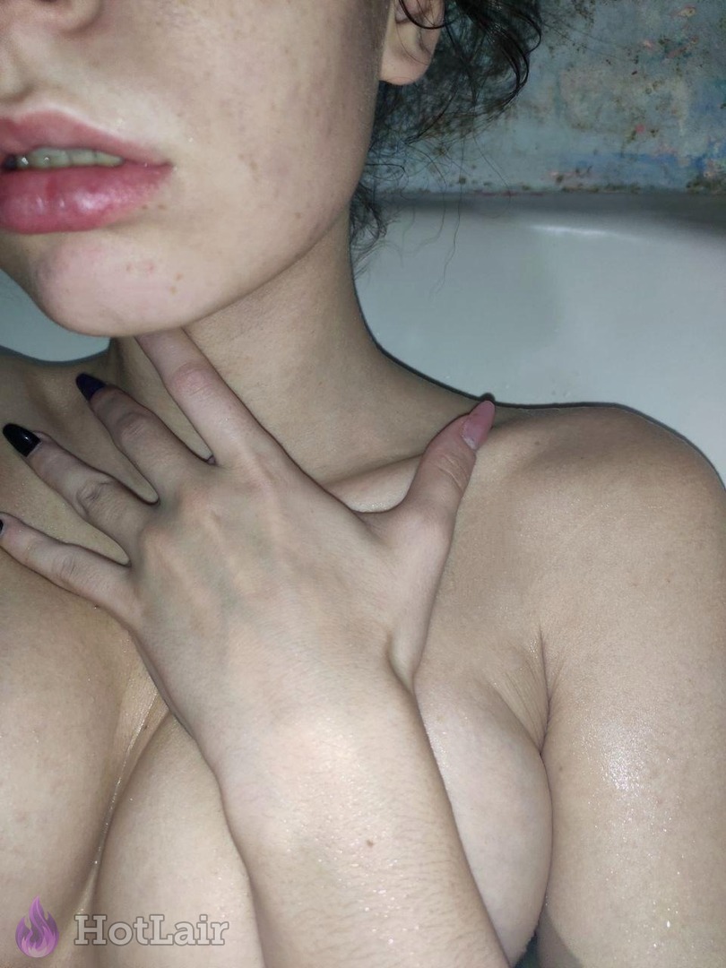 mojada en la bañera con mano en cuello y pecho