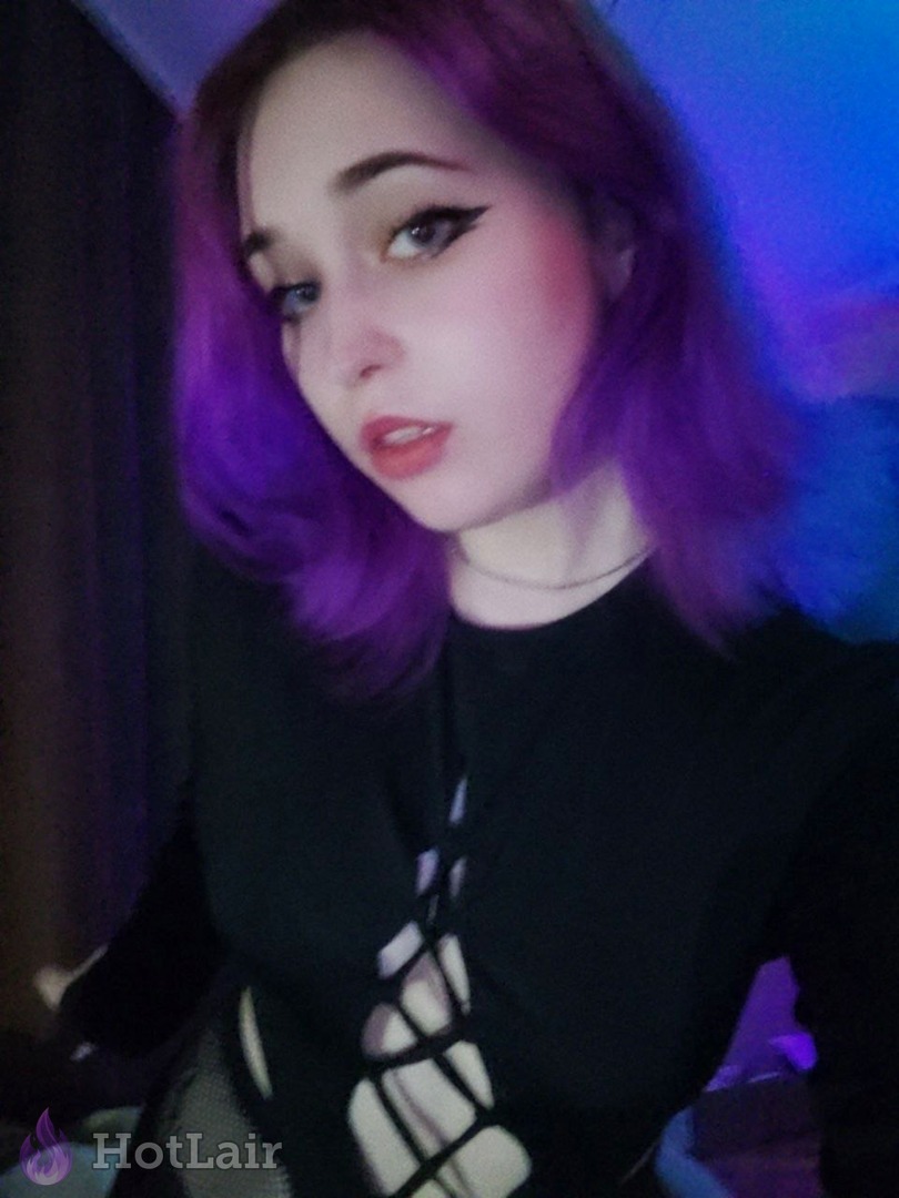 mujer con cabello morado vibrante haciendo selfie en top negro con cortes