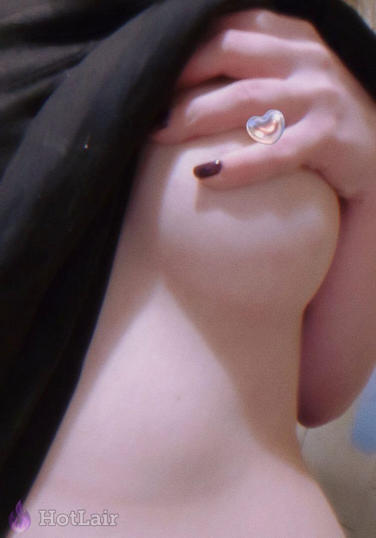 Primer plano de pecho femenino sostenido por mano con anillo en forma de corazón