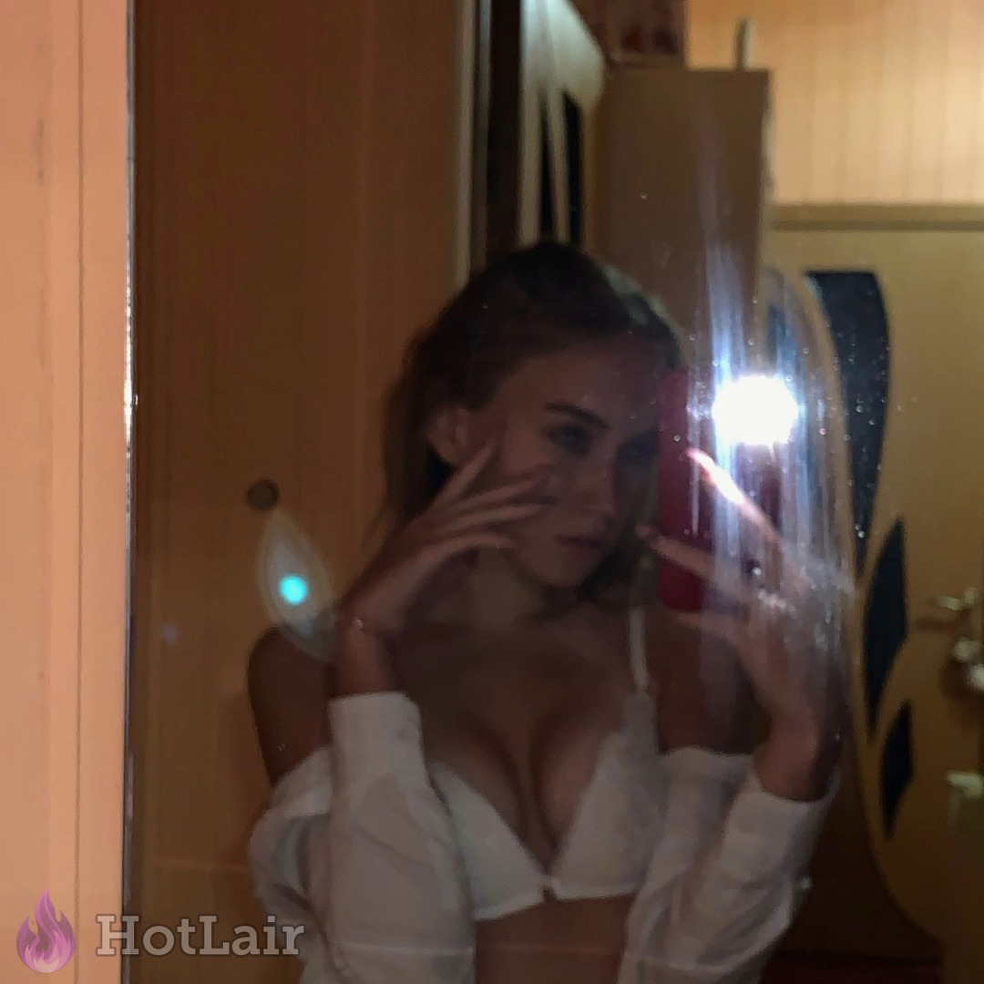 mujer haciendo selfie en el espejo en sujetador blanco de encaje y camisa blanca abierta