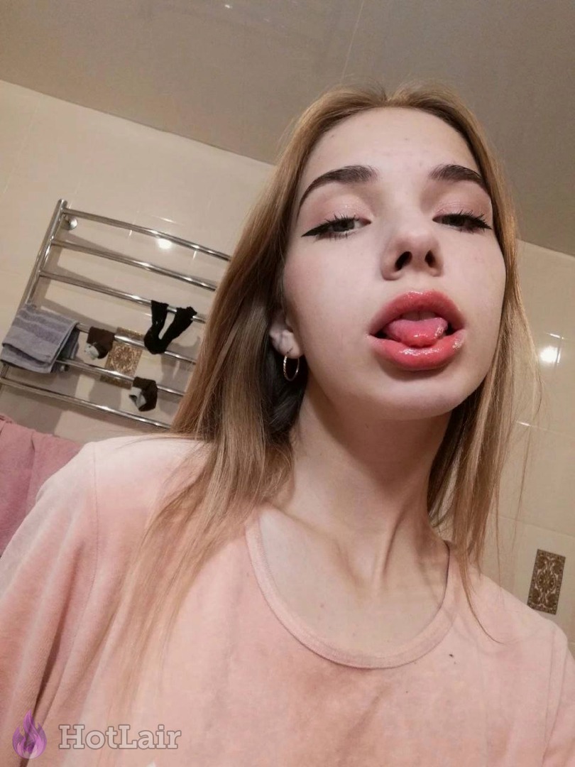 Blonde se prenant en selfie, langue tirée de manière joueuse dans la salle de bain