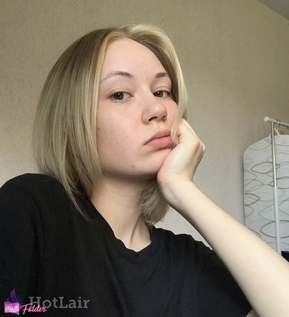 Primer plano de rubia con corte bob en camiseta negra, mano en la mejilla, expresión neutra