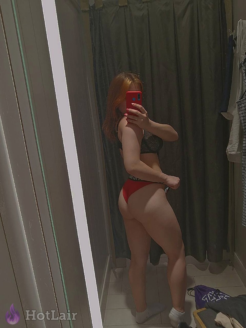 Femme en soutien-gorge noir et string rouge prenant un selfie miroir dans la salle de bain