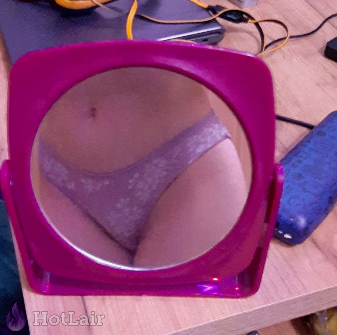Gros plan de la partie inférieure du corps d’une femme en culotte dentelle reflétée dans miroir rose sur bureau