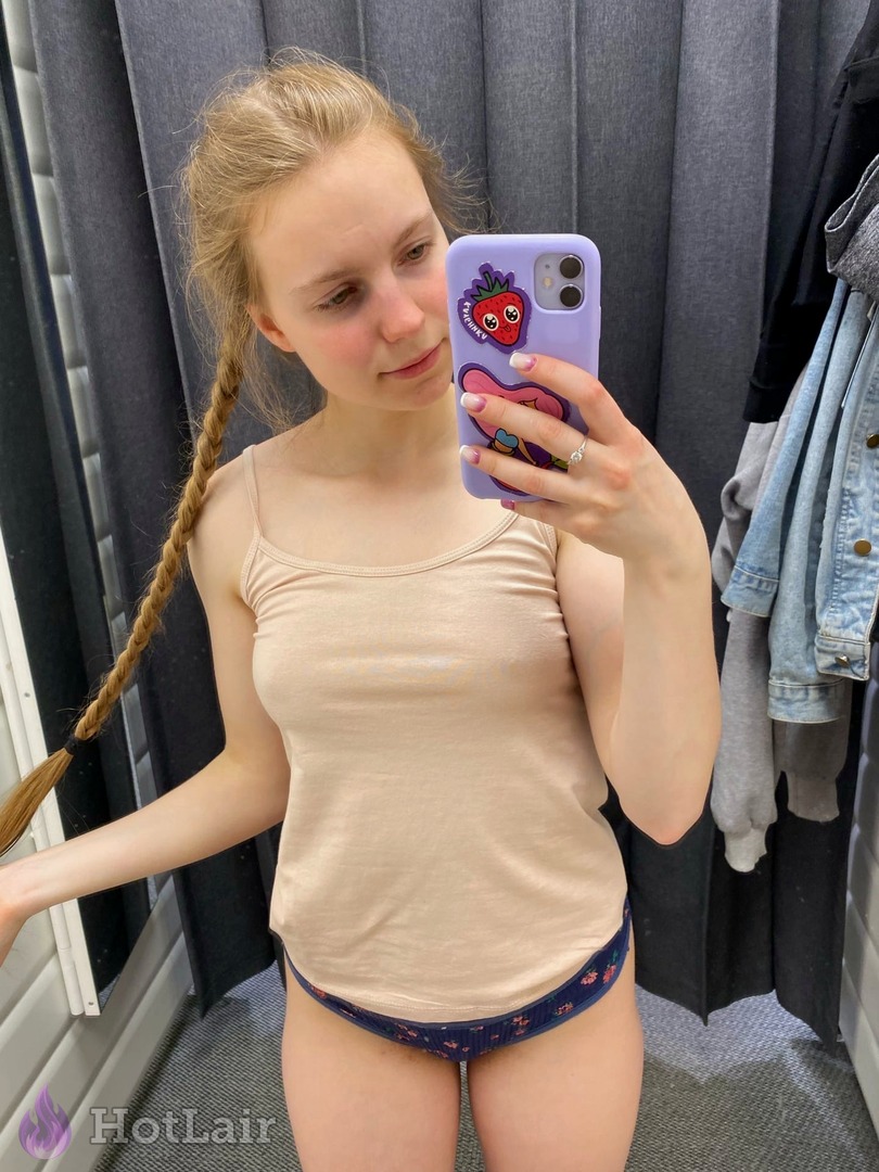 rubia con trenza haciéndose un selfie en el espejo con top beige y braguitas florales