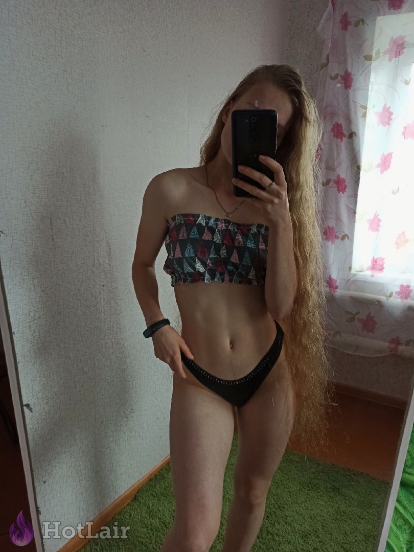 con largo cabello rubio haciéndose un selfie en el espejo con top bandeau estampado y braguitas negras