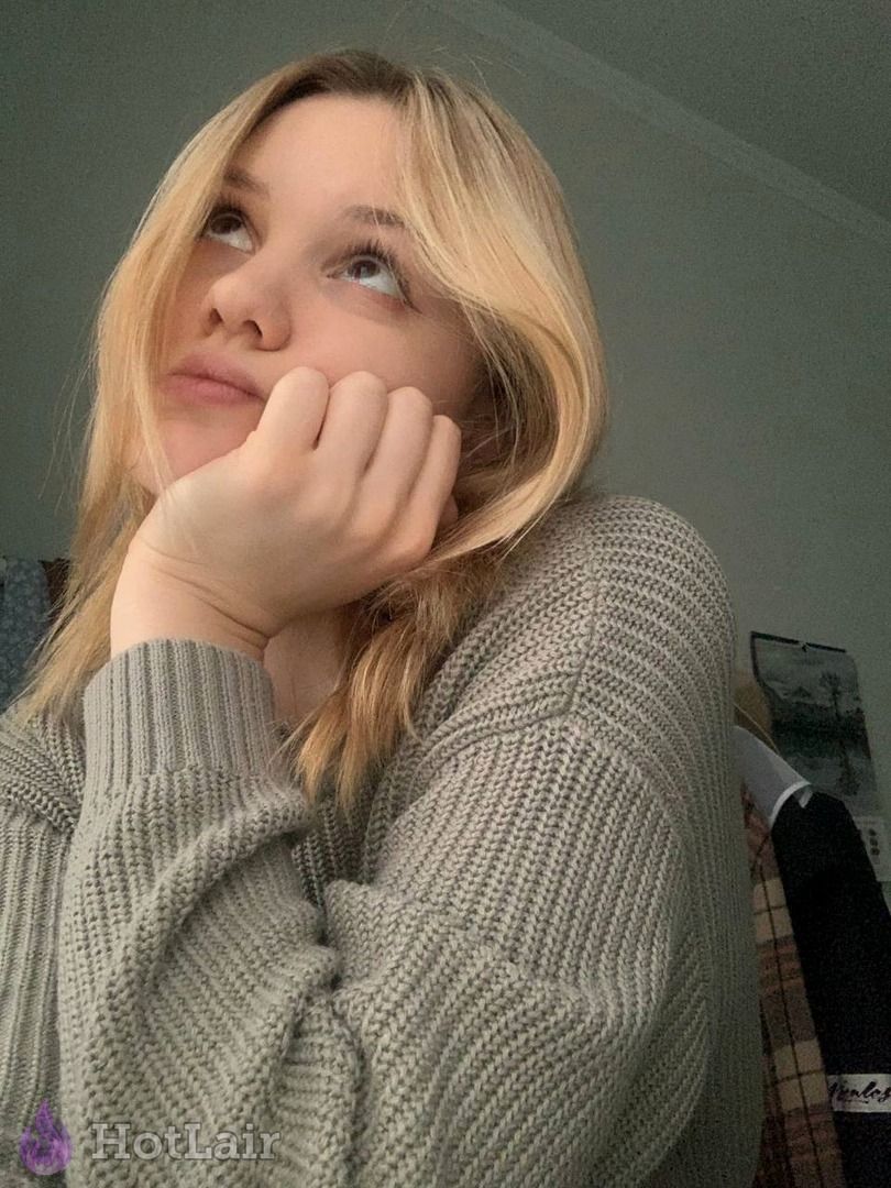 rubia en jersey gris de punto apoyando la barbilla en la mano