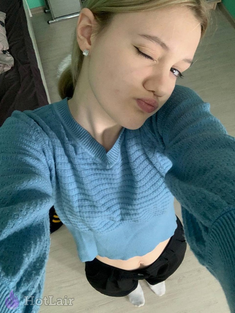 Mujer en jersey azul recortado haciéndose un selfie en interiores