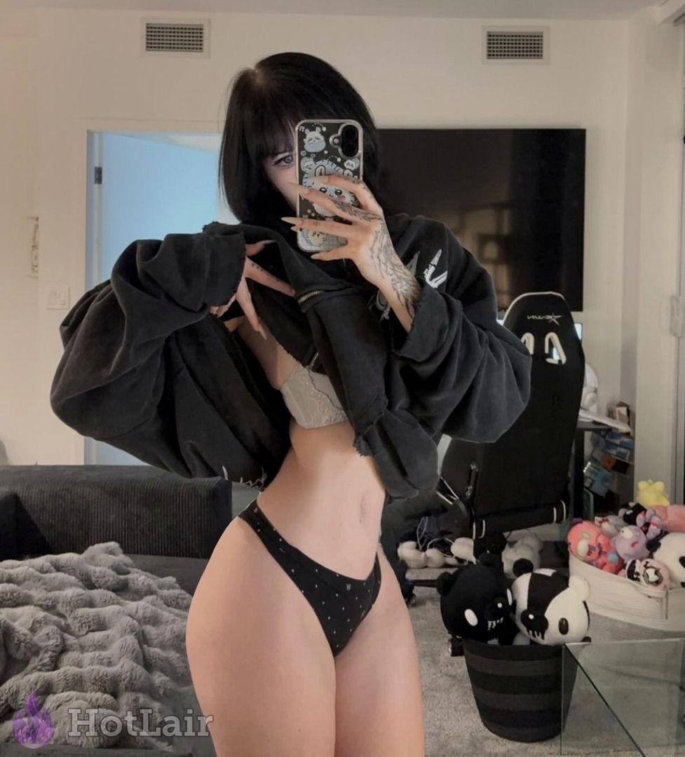 Morenita con tatuajes abriendo una sudadera negra para mostrar sujetador de encaje y bragas negras de lunares, selfie en espejo