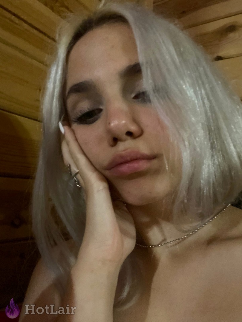 Primer plano de rubia platino con mano en la mejilla en interior de madera