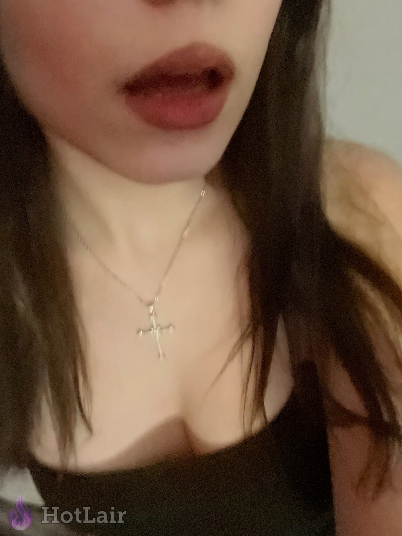 Primer plano de cara de mujer con labial oscuro y collar de cruz plateada