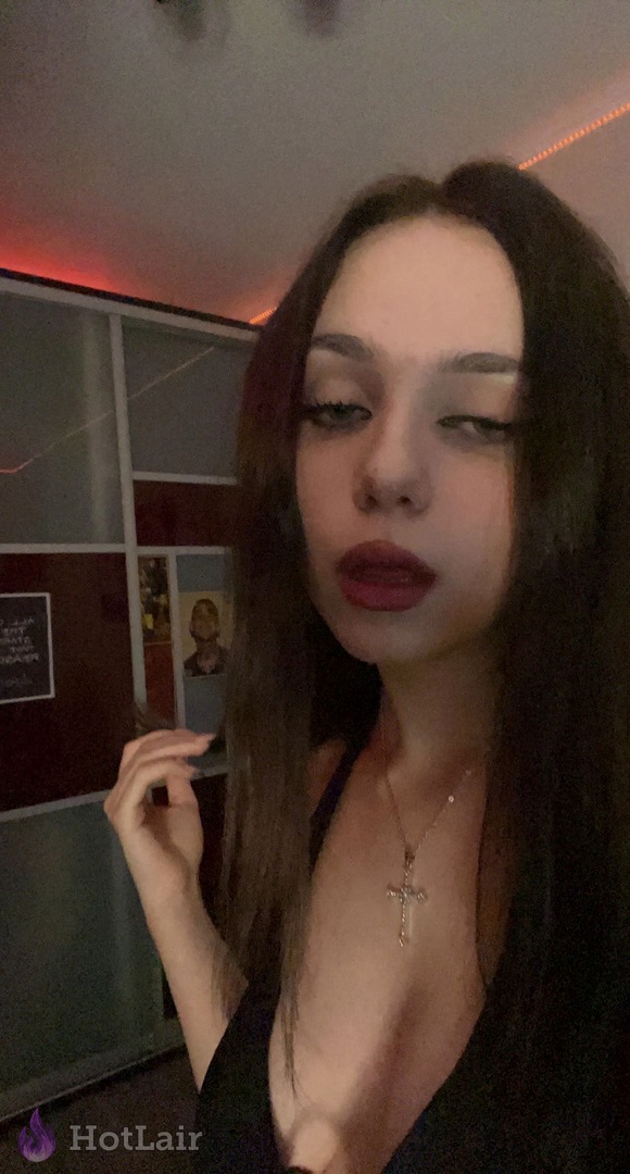 Mujer morena en top negro haciéndose selfie close-up con lengua afuera