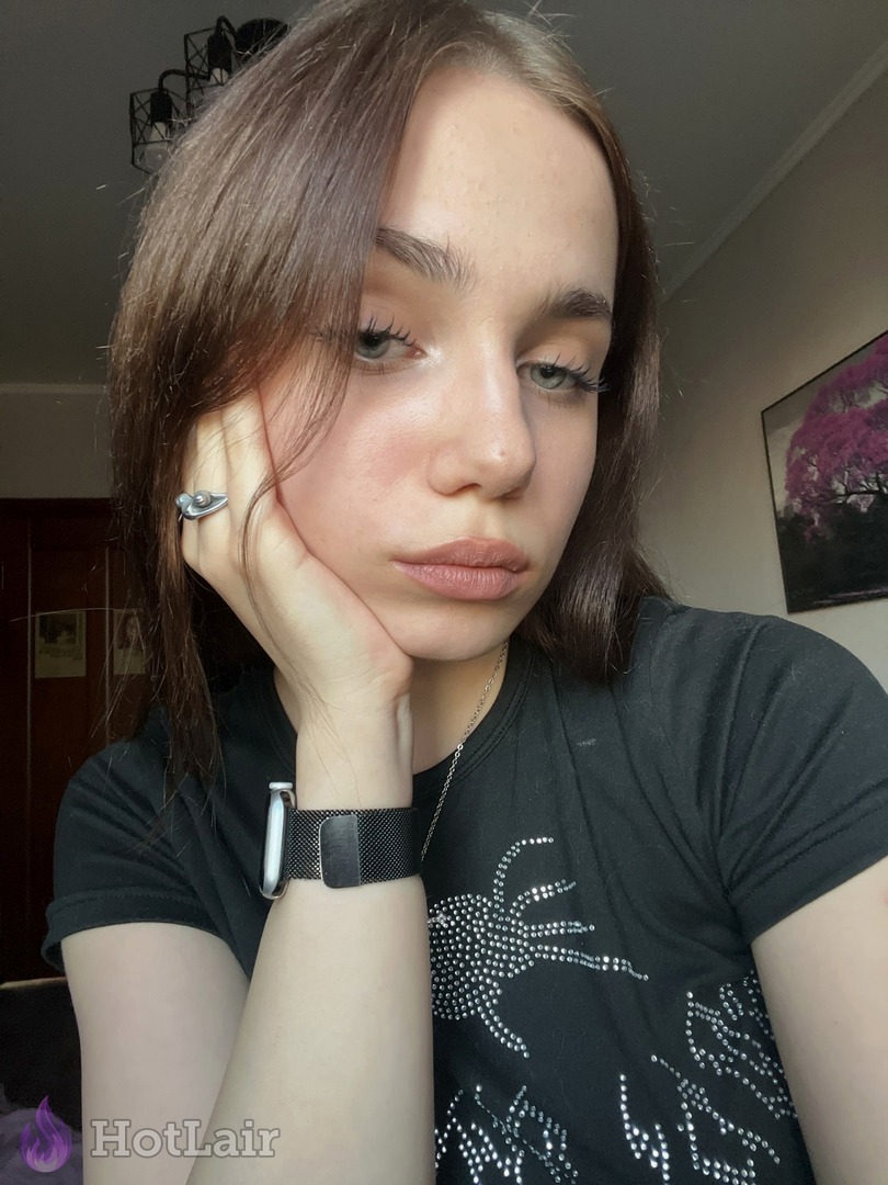 con cabello castaño en camiseta negra con strass, mano bajo la barbilla, primer plano