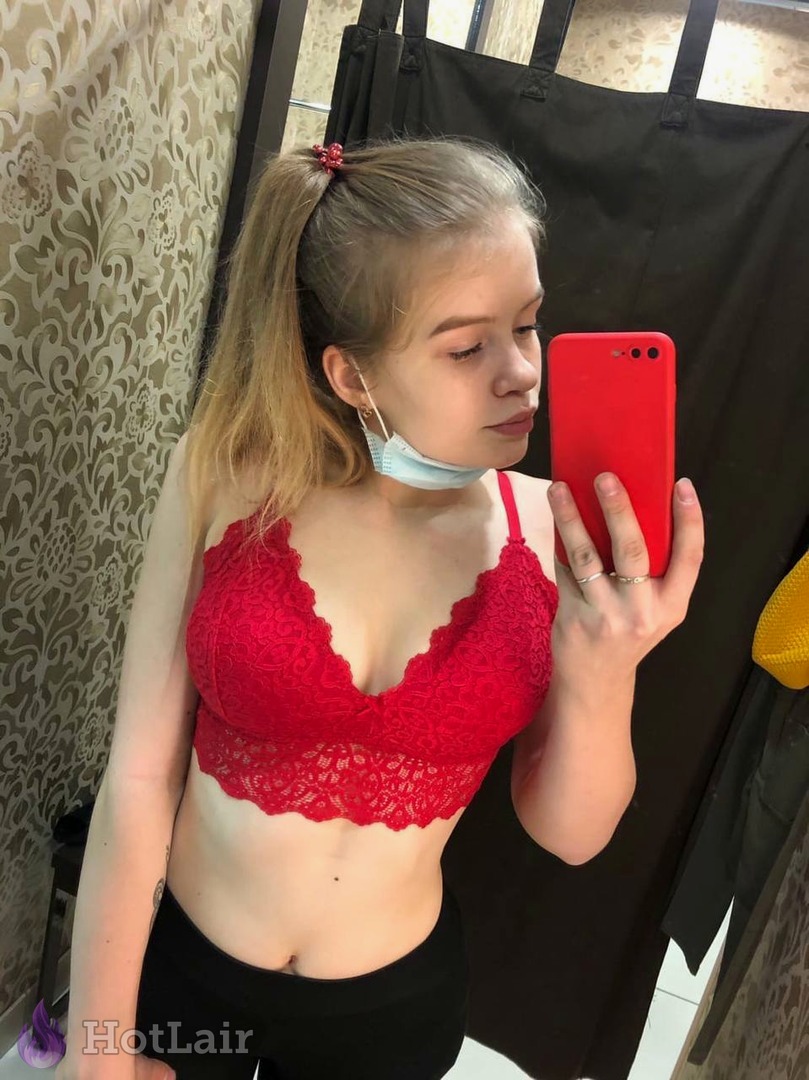 en bralette rojo de encaje haciéndose selfie en espejo, mano en la cadera