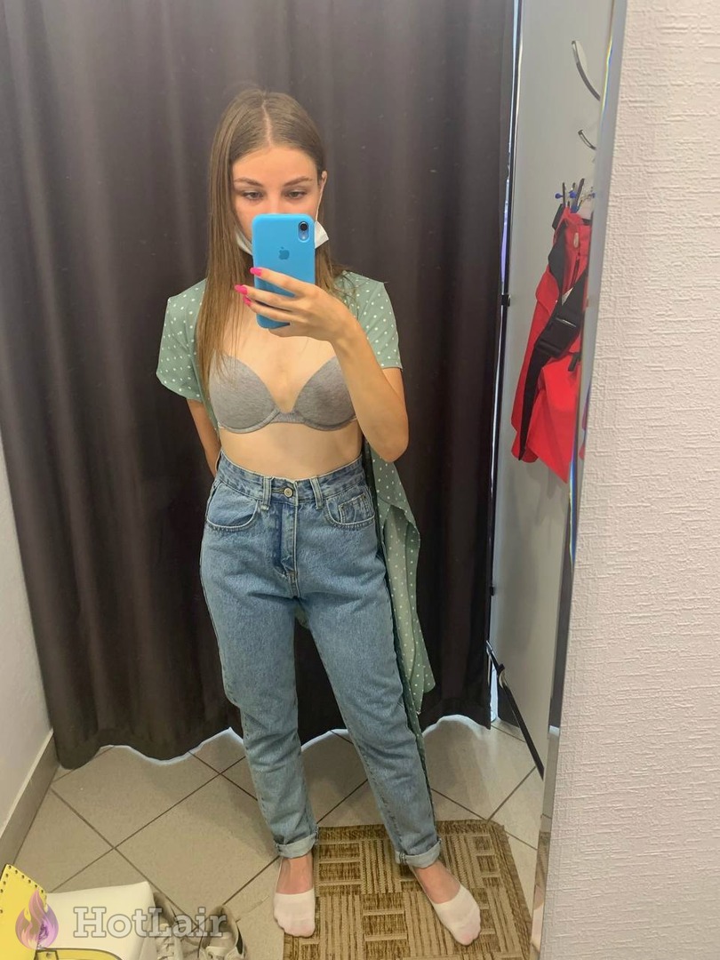 en sujetador gris y jeans haciéndose selfie de cuerpo entero en espejo
