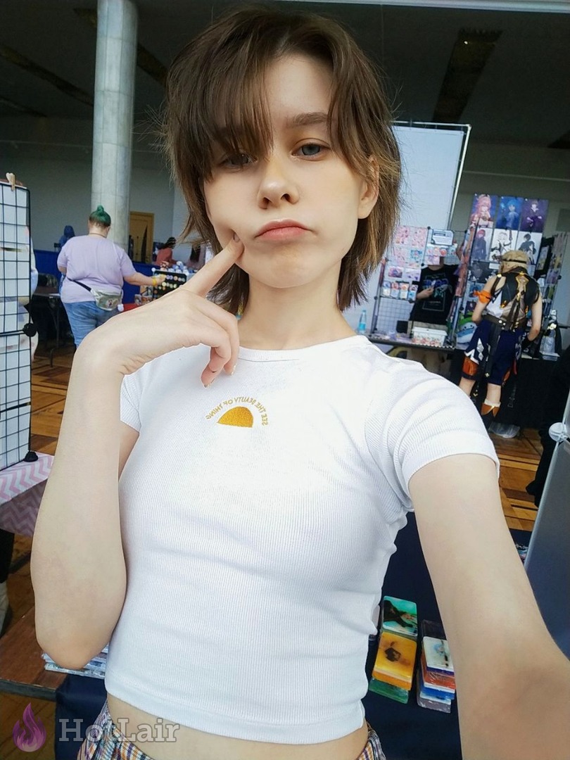 Jeune femme en crop top blanc faisant une grimace drôle en selfie lors d’un événement indoor