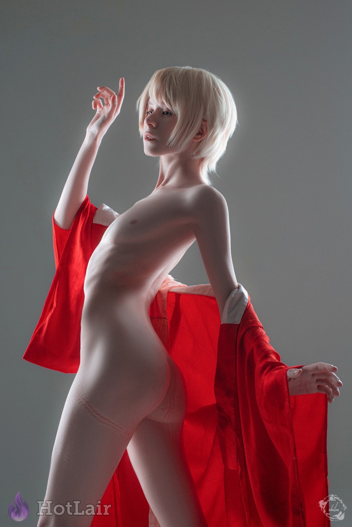 Blonde nue élégante aux cheveux courts platine drapée d’un kimono rouge glissant en studio minimaliste