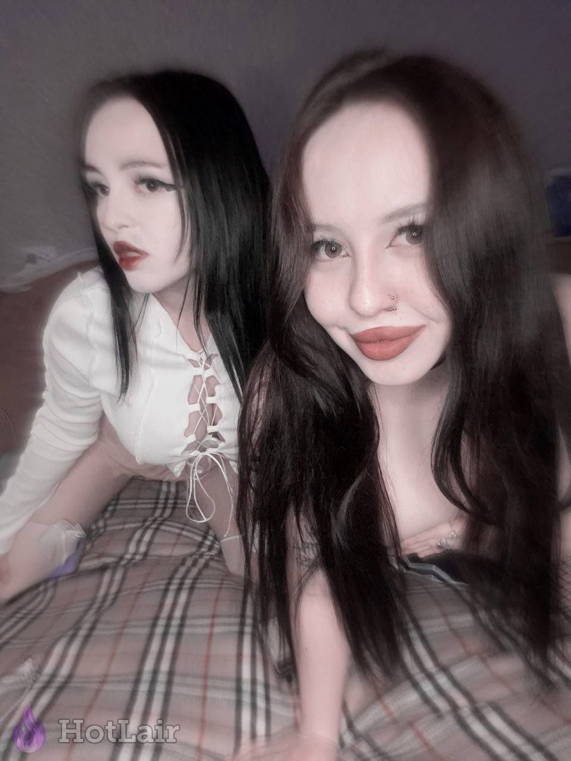Dos jóvenes tumbadas en la cama haciéndose selfie, una con top blanco y otra sonriendo a la cámara