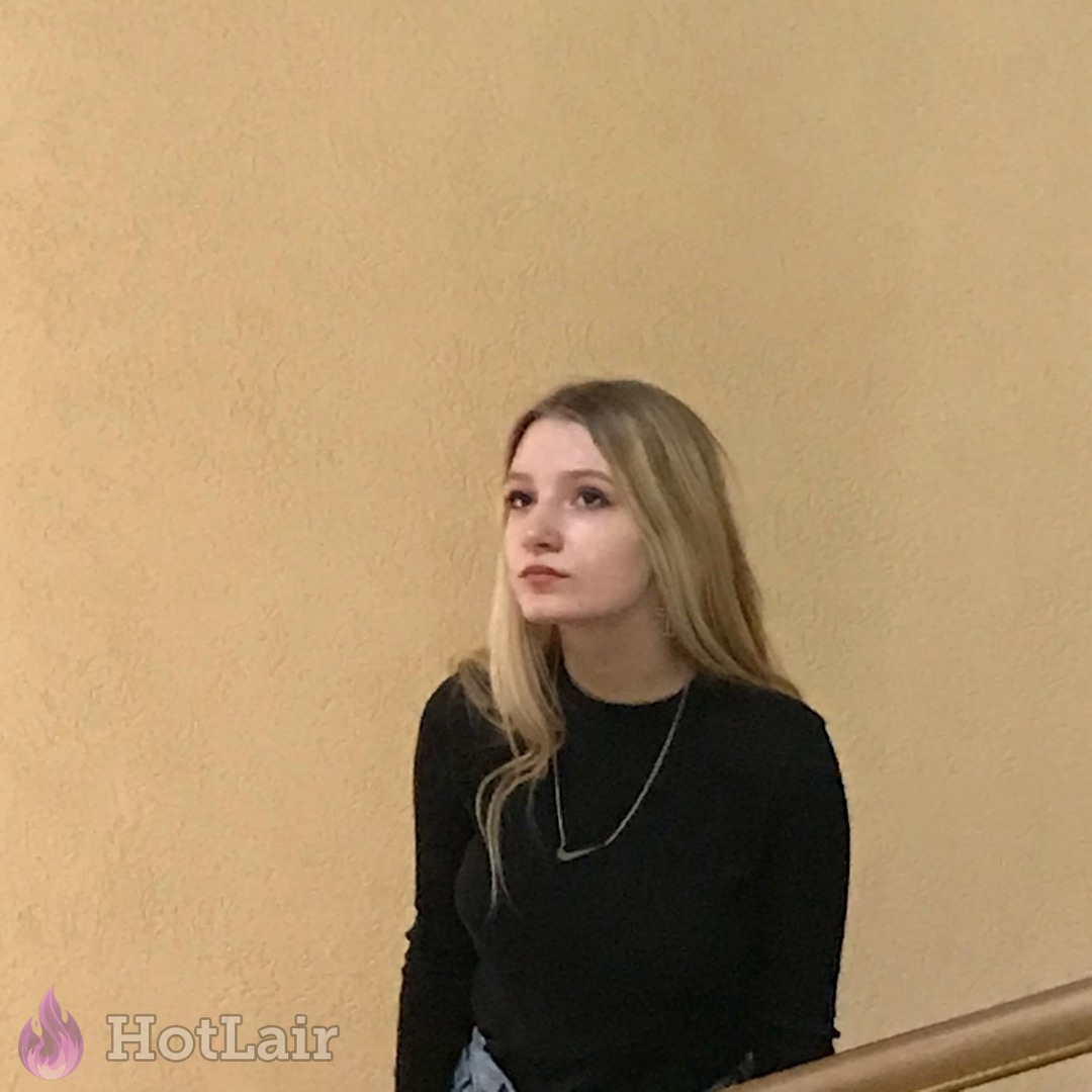 rubia en top negro de manga larga de pie junto a la pared mirando hacia un lado