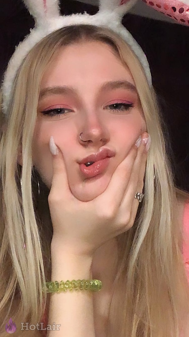 Primer plano adorable de rubia con diadema de orejas de conejo haciendo cara de beso con manos en las mejillas