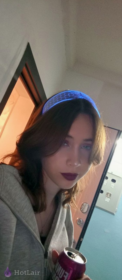 Morena con diadema azul y sudadera gris sosteniendo una lata de bebida en interior