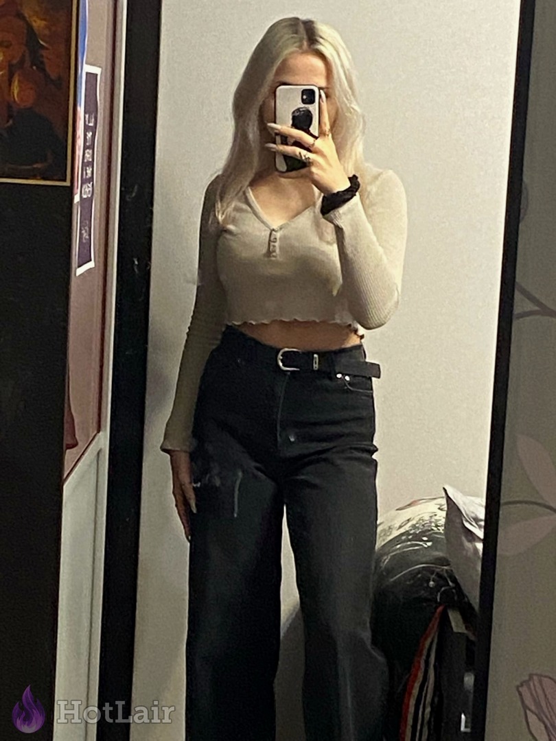 Selfie de cuerpo entero de rubia en crop top beige y jeans negros