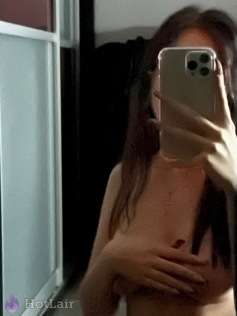 Mujer topless de largo cabello oscuro cubriéndose los senos en selfie de espejo