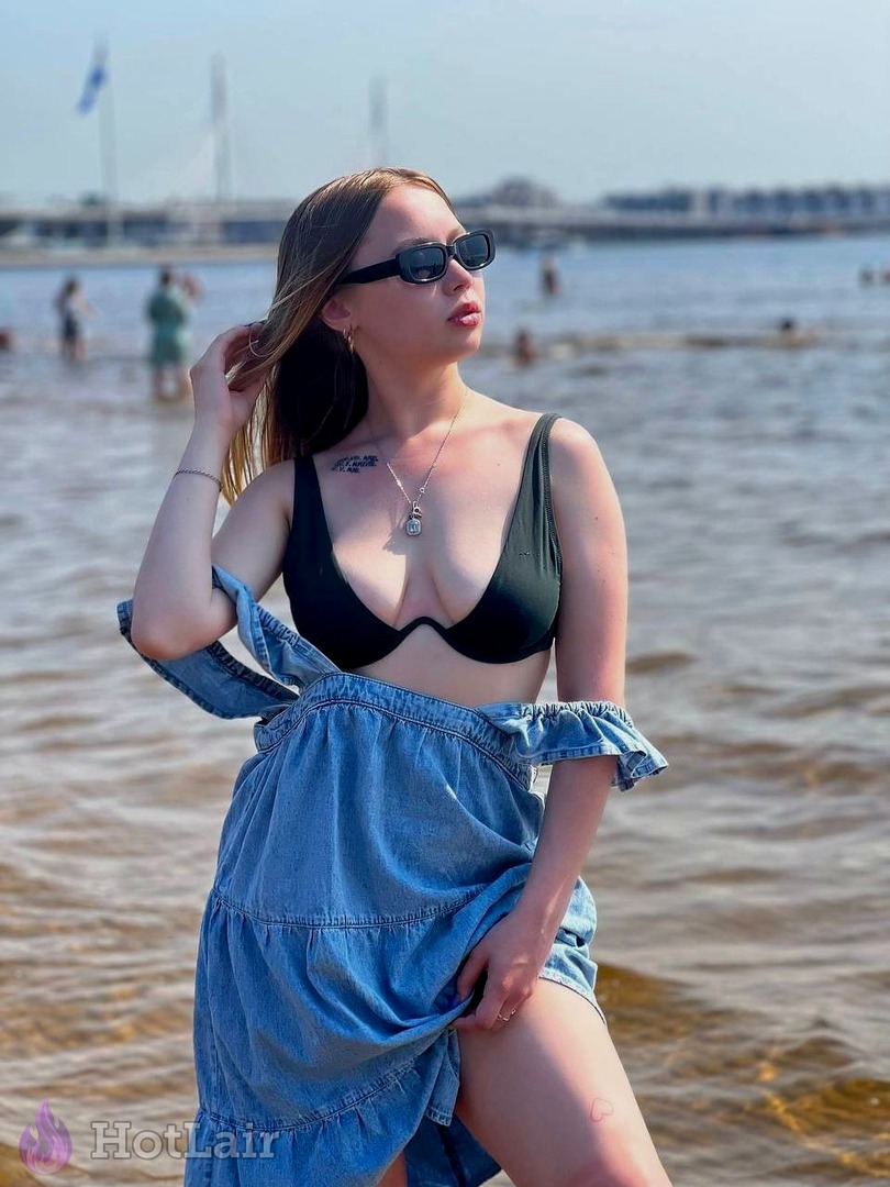 en top de bikini negro y falda vaquera posando junto al agua
