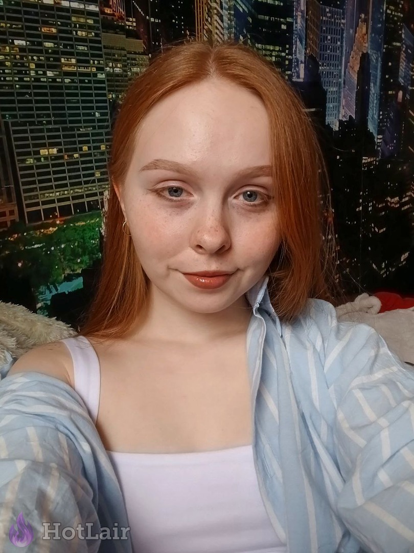 Pelirroja con pecas mira a la cámara con camisa a rayas bajo suave luz natural