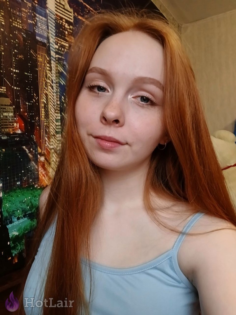 Primer plano de retrato de pelirroja sonriente con pecas y ojos azules en camiseta azul clara