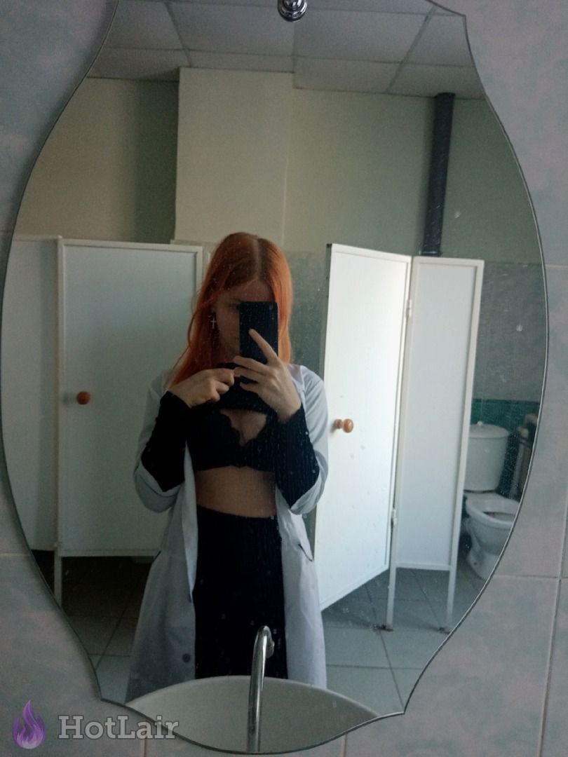 Pelirroja tomando selfie en espejo en el baño con sujetador negro y bata blanca