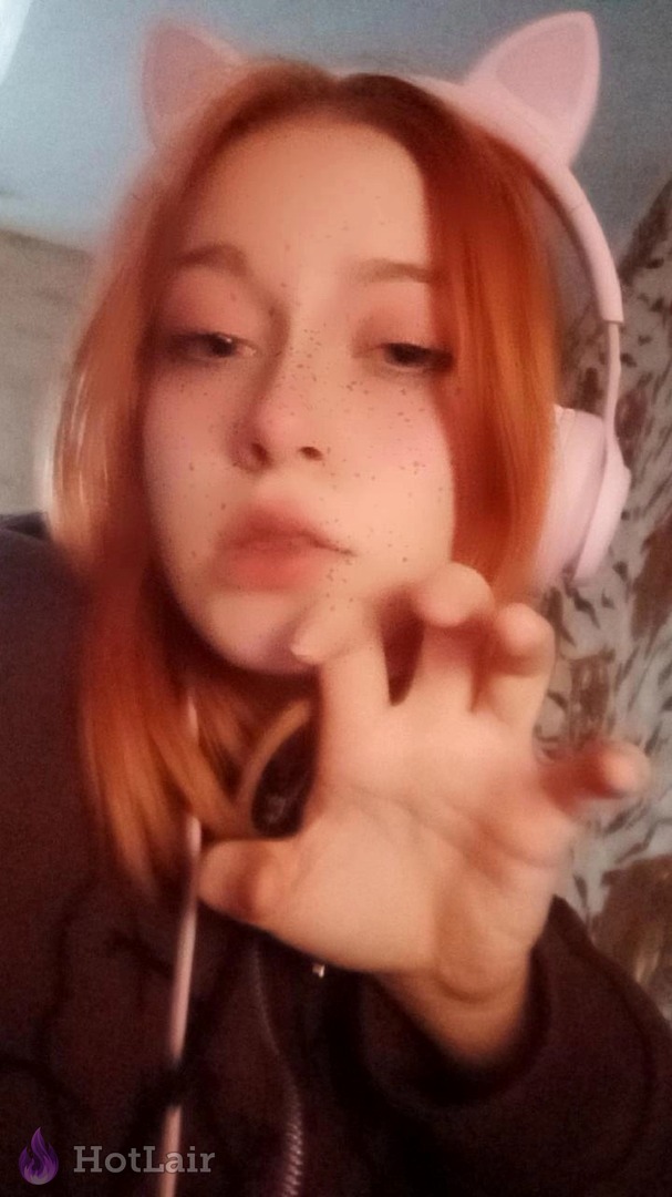 pelirroja con orejas de gato y auriculares tomando selfie cercano