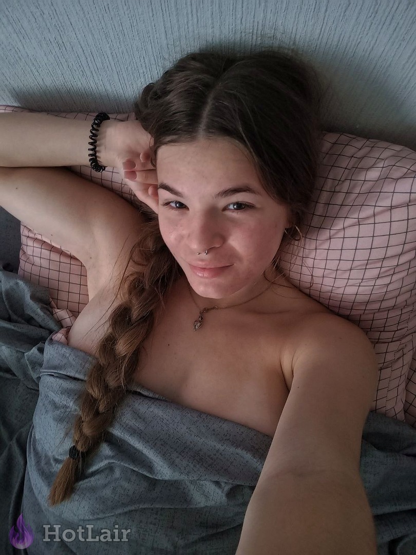 con trenza tumbada en la cama sonriendo a la cámara